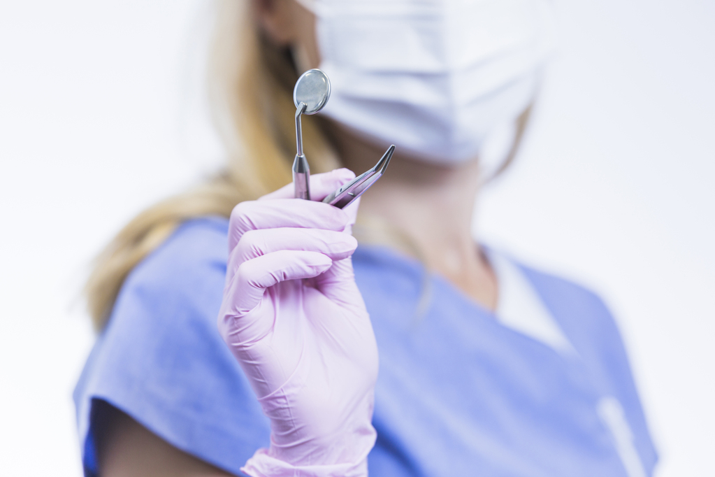 close-up-dentist-pink-gloves-holding-dental-instruments.jpg