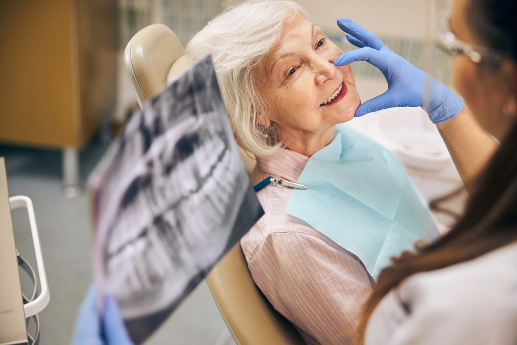 portrait-smiling-female-patient-sitting-dental-chair-while-woman-doctor-touching-face-client.jpg