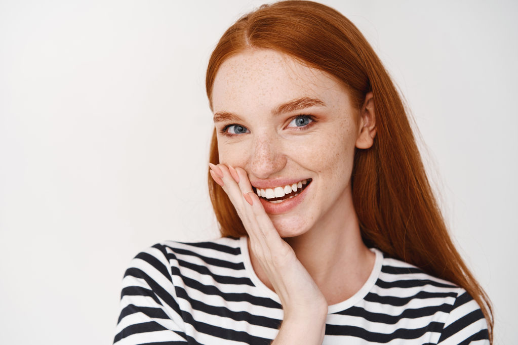 closeup-teenage-redhead-girl-with-freckles-blues-eyes-looking-front-touching-clean-healthy-skin-face-smiling.jpg