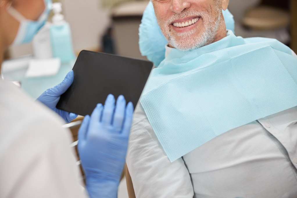 dental-expert-holding-tablet-while-having-appointment-with-elderly-man.jpg